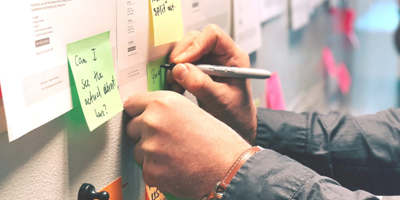 Person writing on a post-it note on a wall